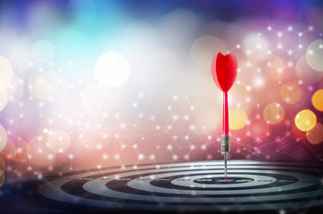 Close up shot red dart arrow on center of dartboard over bokeh background