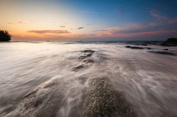 Obraz premium waves trails and beautiful sunset sky. soft focus due to slow shutter and water movement.