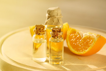 essential orange oil . oil orange in transparent glass bottles and orange slice on a round wooden board on a blurred beige background. organic cosmetics concept