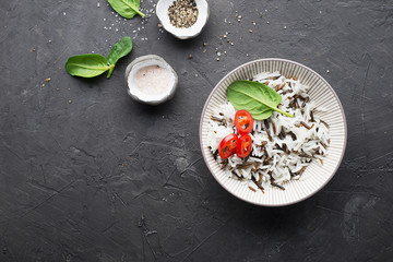 A mixture of ready boiled wild and basmati rice with rings of hot red pepper on a dark background. Top View.