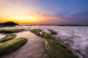 view of beautiful sunset with rocks covered by green moss at Kudat, Sabah Malaysia. image contain...