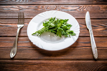 Diet concept.A bunch of parsley lies on a white plate.