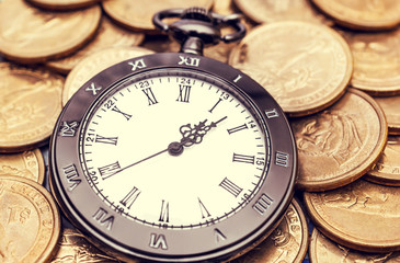 Pocket watch on the golden coins. Business concept. Toned image.