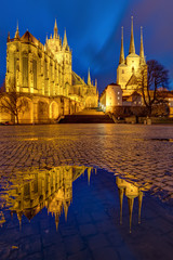 The famous Cathedral and Severi church in Erfurt at dusk reflected in a puddle	
