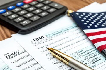 Fototapeta premium Tax forms with small american flag and calculator on the table. Business concept.