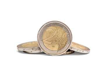 Two euro coin with heap of euro coins on white background.
