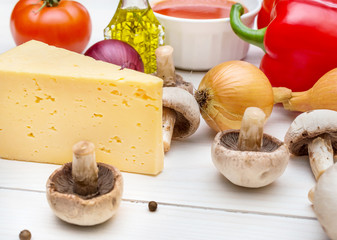 Raw ingredients for pizza on white wooden table.