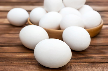 Eggs and wooden bowl with eggs on the table.