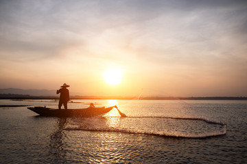 Fototapeta premium Asian fisherman throwing fishing net in lake at sunrise time.(Lifestyle of the population living in the river)