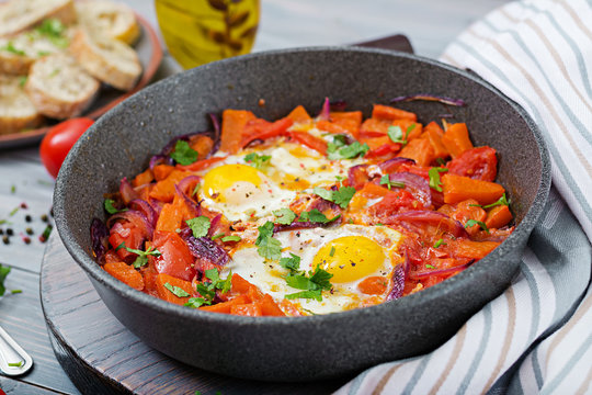 Fried eggs with pieces of pumpkin, red onions and tomatoes. Tasty breakfast.