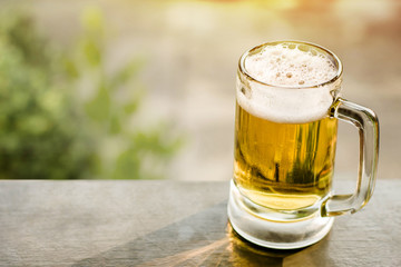 Drinking Beer in Summer Concept. Glass of Beer on Balcony. Natural Sunlight and Tree as background, Warm Tone
