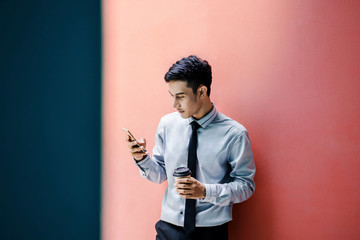 Happy and friendly young attractive Businessman use a Smart phone at colorful wall, Social communicate technology in business concept, Lifestyle of modern male