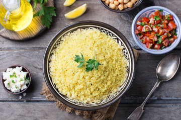 Couscous in bowl. Wooden background. Top view.
