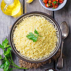 Couscous in bowl. Wooden background. Top view.