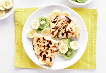 Crepes with banana, kiwi slices and chocolate sauce