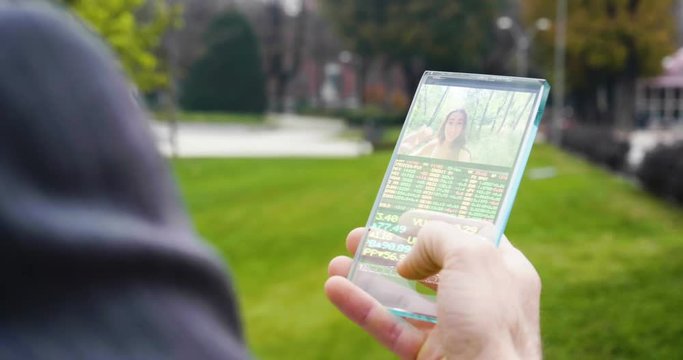 A man answers the wife who smiles and waves from the phone that appears in hologram clock futuristic and technological. Concept: holiday, communication,family, technology, augmented reality and future
