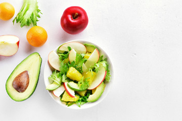 Fruit vegetable salad with red apples, avocado, orange slices