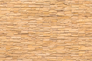 Rock stone brick tile wall aged texture detailed pattern background in dark yellow cream  brown color