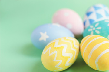 Pastel and colorful easter eggs with copy space on green background.