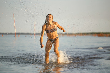 water fun. the girl runs along the seashore.