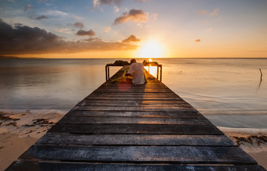 sunset seascape with wooden jetty toward horizon.