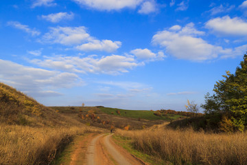 Fototapeta na wymiar Autumn in the countryside. Dirt road between the hills