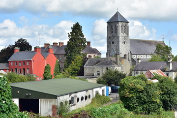 Fototapeta premium Old stone church of Saint Coca behind mostly industrial buildings in small Irish town of Kilcock in 2017.