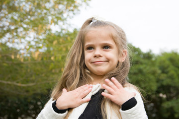 cute little blond girl in park emotional face