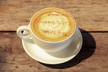 Hot coffee cappuccino in white cup decorated on wooden background.