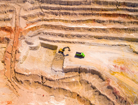 Aerial view of a working excavator in the open cast mine. Heavy industry and machinery. Industrial background on mining theme. 