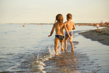 Girl and boy are running along the sea shore