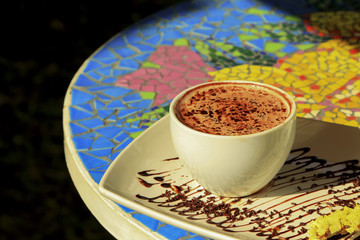 Hot coffee mocha in white cup on white dish decorated with chocolate .