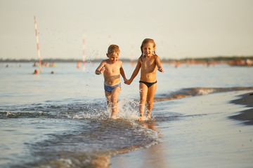 Girl and boy are running along the sea shore