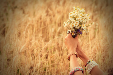 Girl holding flowers in a wheat field.