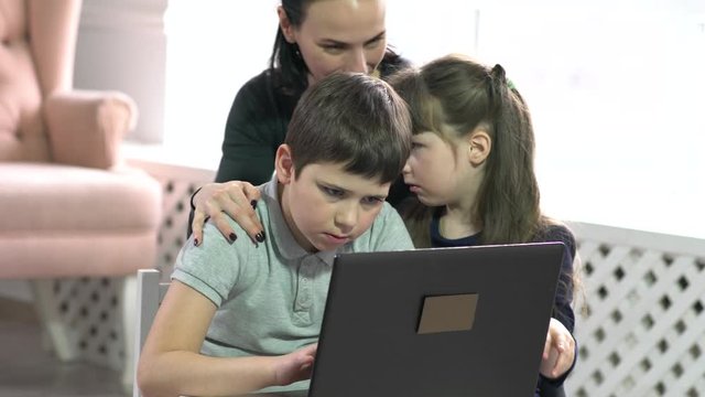 Mom and kids having fun on laptop at home.
