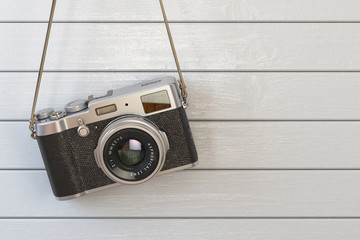 Vintage retro photo camera hanging on the white wooden wall.