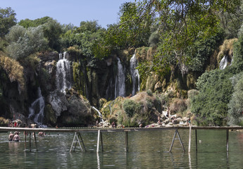 Fototapeta na wymiar Kravice waterfalls in Bosnia Herzegovina, with a floating wooden bridge