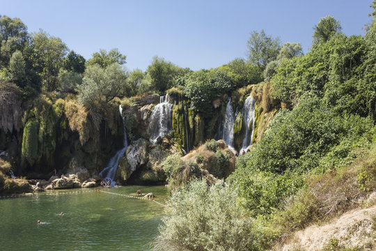 Scenic view of Kravica waterfalls in Bosnia Herzegovina, with few people under the stream © greta gabaglio