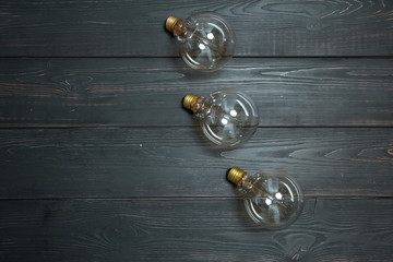 Three edison lamps with a beautiful spiral on a black textured wooden background