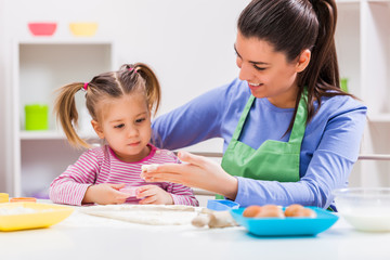 Happy mother and daughter are making cookies in their kitchen. 