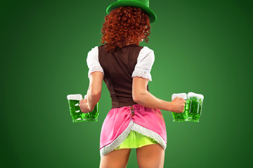 St Patricks Day. Young sexy Oktober fest waitress, wearing a traditional Bavarian dress, serving...