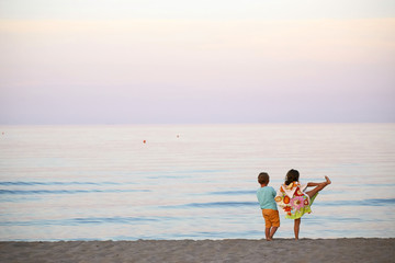 Fototapeta premium children boy and girl romance on the seashore colorful sunset.
