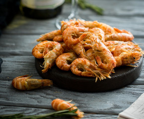 Fresh shrimps served on a wood plate with garlic, spices and rosemary with a glass of champagne (sparkling white wine).