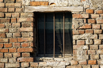 Old brick wall with brick filled window with grid.