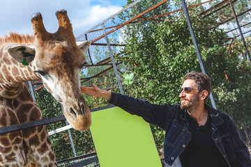 man with a beard stroking the head of a giraffe