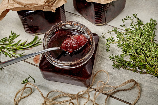 Jam with rosemary on wooden background with chopping board in kitchen table. Top view.
