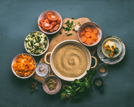 Couscous And Various Healthy Organic Diced Vegetables Ingredients In Bowls With Glass Jar For Lunch Making, Top View. Vegetarian Eating And Cooking Concept