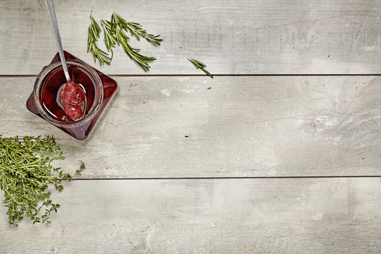 Jam with rosemary on wooden background with chopping board in kitchen table. Top view.