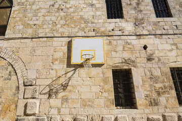 Basketball basket on the wall of monastery. Outdoor activity location.