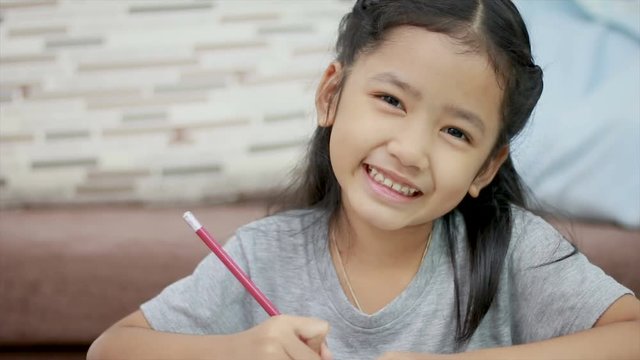 Asian little girl doing homework and smiling with happiness with copy space composition 
